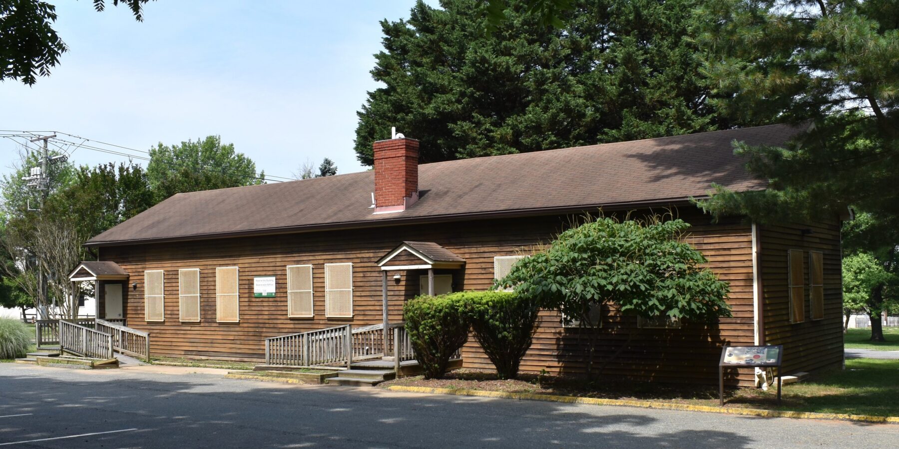 one story brown school buildings with central chimney and parking lot